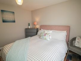 A bedroom with a gray bed and nightstand at Hazel Cottage in Portrush