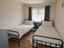 A bedroom with two single beds and a window at Hazel Cottage Portrush