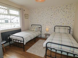 A bedroom with two beds and a bedside table at Hazel Cottage in Portrush