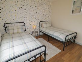 A bedroom with two single beds and a bedside table at Hazel Cottage in Portrush