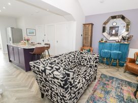 A living room with a sofa, kitchen island and bar stools at Pengwern in Llanrwst