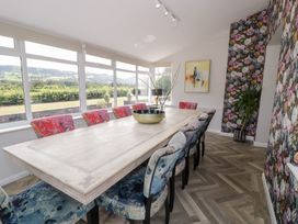 A dining room with a large table and colorful chairs at Pengwern in Llanrwst