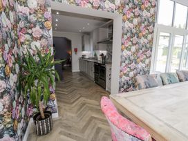 A dining room with a kitchen visible at Pengwern in Llanrwst