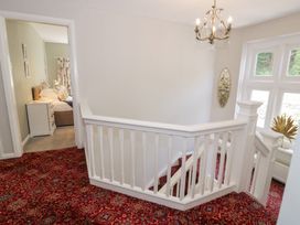 A staircase with a chandelier and a mirror at Pengwern in Llanrwst