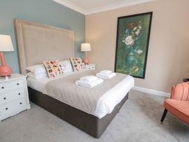 A bedroom with a bed, bedside tables, lamps, and a painting at Pengwern in Llanrwst