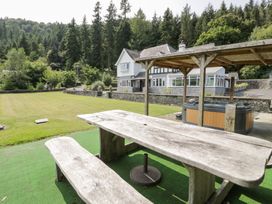 An outdoor area with a table and hot tub at Pengwern in Llanrwst