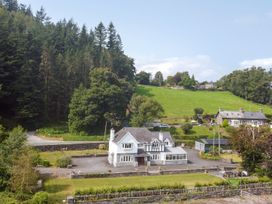 A house with garden and trees in the background at Pengwern Llanrwst