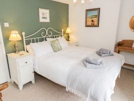 A bedroom with a double bed two bedside tables with lamps a wooden desk and paintings at Afallon in Penmachno