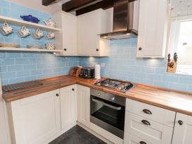 A kitchen with white cabinets wooden countertops blue tiled backsplash and kitchen appliances at Afallon in Penmachno