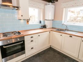 A kitchen with wooden countertops white cabinets blue tile backsplash and stainless steel oven at Afallon in Penmachno