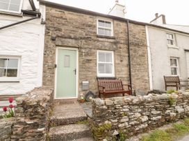 A stone house with a light green door and two wooden benches outside at Afallon in Penmachno