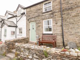 Stone cottage exterior with a light green door wooden bench and stone wall at Afallon in Penmachno