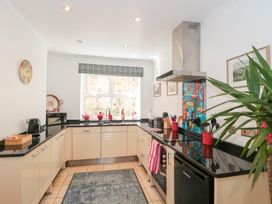 A kitchen with cabinets black countertops a stove a hood and a window with plants on the sill at The Hideaway in Malvern