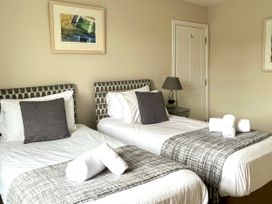 A bedroom with two beds, a lamp, and artwork at Seasides in Weymouth