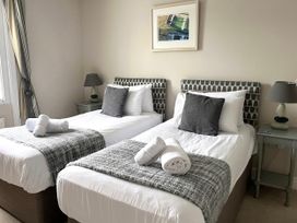 A bedroom with twin beds and a bedside table at Seasides in Weymouth