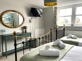 A bedroom with two beds and a mirror at Seasides in Weymouth