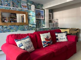 A living room with a red sofa and foosball table at Seasides in Weymouth