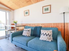 A living room with a blue sofa two cushions a floor lamp and a table with stools at 194 Atlantic Bays Atlantic Bays Holiday Park near St Merryn