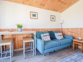 A living area with a blue sofa and patterned cushions a wooden table with stools and a vase of yellow tulips at 194 Atlantic Bays Atlantic Bays Holiday Park near St Merryn