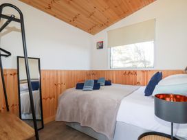 A bedroom with a bed towels a standing mirror wooden ceiling and window at 194 Atlantic Bays in Atlantic Bays Holiday Park near St Merryn