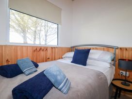 A bedroom with a bed with pillows towels and a side table with a lamp at 194 Atlantic Bays in Atlantic Bays Holiday Park near St Merryn