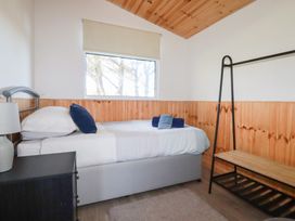A bedroom with a single bed a bedside table with a lamp and an open clothes rack at 194 Atlantic Bays Atlantic Bays Holiday Park near St Merryn