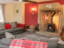 A living room with a fireplace a grey sofa and chairs with red and grey cushions at Belmont Bridge in Henlle