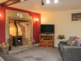 A living room with a fireplace and a television on a wooden cabinet at Belmont Bridge in Henlle