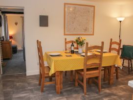 A dining room with a table covered in a yellow polka dot tablecloth set for four with wooden chairs at Belmont Bridge in Henlle