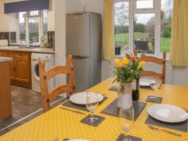 A kitchen and dining area with a yellow polka dot tablecloth wooden chairs a refrigerator and a washing machine at Belmont Bridge in Henlle