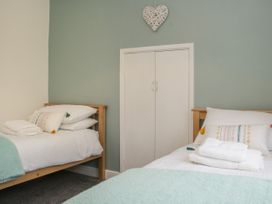 A bedroom with two single beds wooden frames white bedding folded towels closet with double doors and a heart decoration on the wall at Belmont Bridge in Henlle