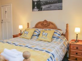 A bedroom with a wooden bed with patterned bedding two yellow deer pillows bedside tables with lamps and a wall photo at Belmont Bridge in Henlle