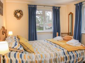 A bedroom with a patterned bedspread a wooden bed frame blue curtains a wall mirror and folded towels on the bed at Belmont Bridge in Henlle
