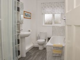A bathroom with a bathtub a toilet a sink a shower enclosure and shelves at Belmont Bridge in Henlle
