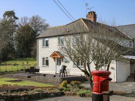 A white two-story house with a garden table set and a red post box in front at Belmont Bridge in Henlle