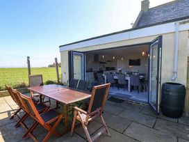 An outdoor dining area with wooden table and chairs at Voebroch in Lythe