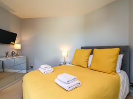 A bedroom with a yellow bedspread and mirrored dresser at Voebroch in Lythe