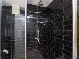 A shower with glass door and black tiles at Voebroch in Lythe