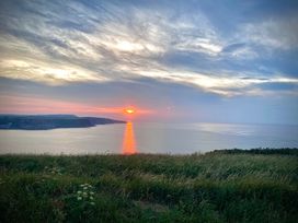 A sunset over the ocean viewed from a grassy hill at Voebroch in Lythe