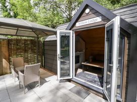 A cabin with an open door and outdoor seating area at Willow Lodge At Bridge Lake Farm & Fishery Chacombe