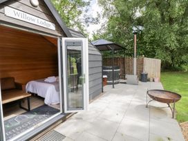 An outdoor area with a lodge, hot tub, and seating at Willow Lodge At Bridge Lake Farm & Fishery Chacombe