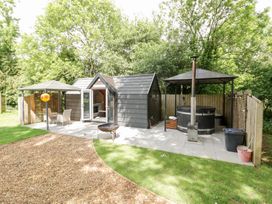 An outdoor garden with a hot tub and wooden cabin at Willow Lodge At Bridge Lake Farm & Fishery Chacombe