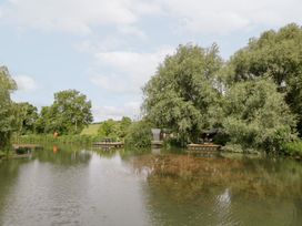 A landscape with water and trees at Willow Lodge At Bridge Lake Farm & Fishery Chacombe