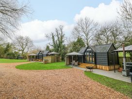 A view of cabins along a gravel pathway at Willow Lodge At Bridge Lake Farm & Fishery in Chacombe
