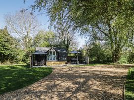 A cabin with a deck and seating area at Willow Lodge At Bridge Lake Farm & Fishery Chacombe