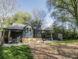 A cabin with a terrace and outdoor seating at Willow Lodge At Bridge Lake Farm & Fishery, Chacombe