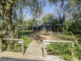 A garden with a cabin and wooden deck at Willow Lodge At Bridge Lake Farm & Fishery Chacombe