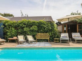 A swimming pool with deck chairs and plants at Barnsley House in Teignmouth