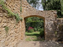 An archway with a stone wall leading to a garden at The Old Bakery South Perrott near Mosterton