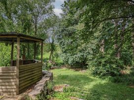 A garden with a wooden gazebo and stone wall at The Old Bakery in South Perrott near Mosterton